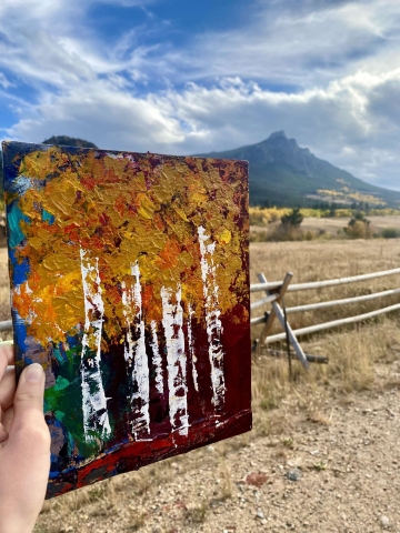 Fall painting of aspen trees with foliage and peaks in background